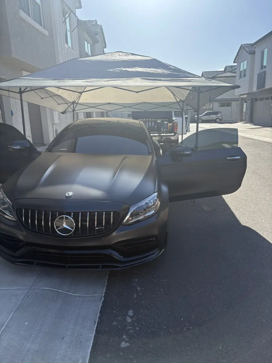 Matte black Mercedes-AMG detailed under a shade canopy
